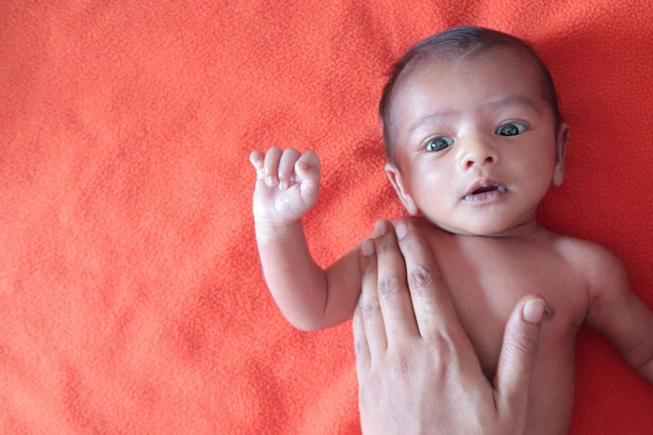 Bayi baru dilahirkan dengan tangan seseorang memegang badannya.